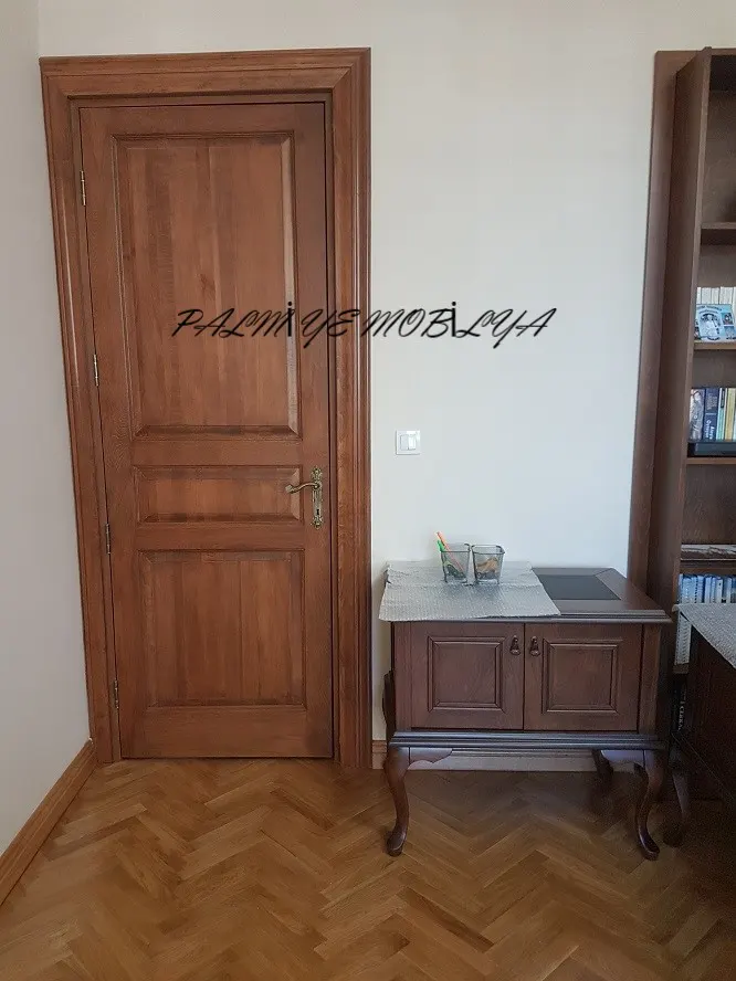 Balıksırtı parkeli çalışma odasında panelli ahşap kapı ve kabriyol ayaklı küçük dolap