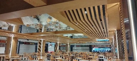 Ahşap çıta kaplı kolonlar ve kirişlerle çevrili yemek alanında akşam aydınlatması