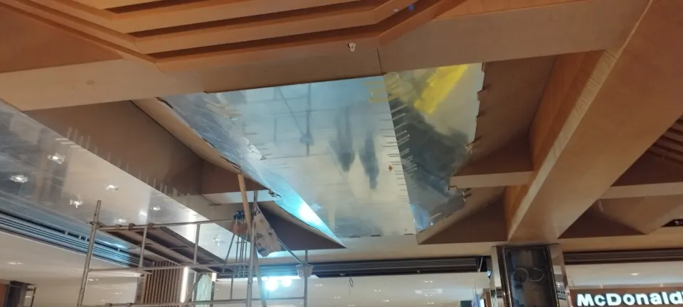 Ahşap kirişli tavanda yerine takılan ayna kaplamalı paneller ve altındaki iskele